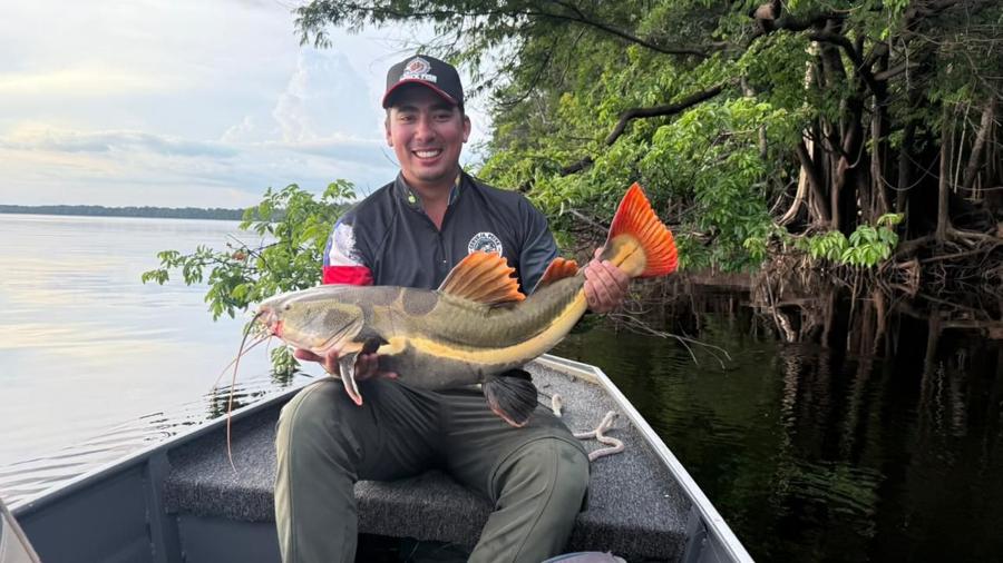 Seated angler with an orange-finned peacock bass