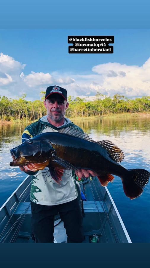 Dark-bodied catch held against blue sky and water