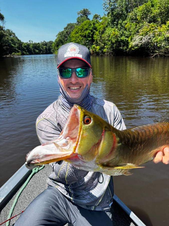 Smiling angler holding a peacock bass on the river