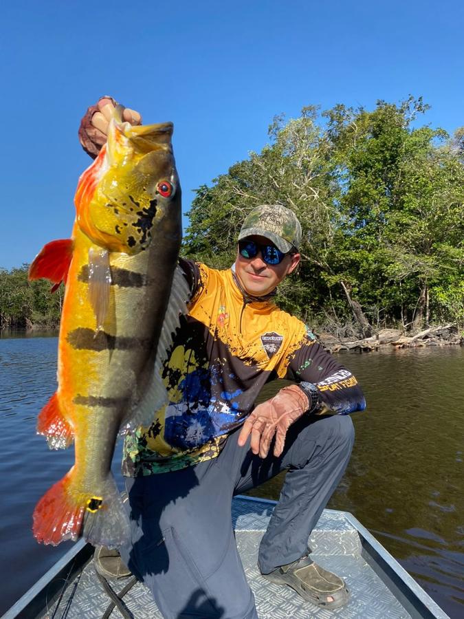 Camouflage-capped angler kneeling with a colorful catch